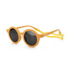 Occhiali da sole zo-oz stile tondo modello Bam giallo opaco con fascetta gialla per bambini 0-2 anni. Inquadratura laterale in prospettiva con le aste aperte appoggiate su una superficie.