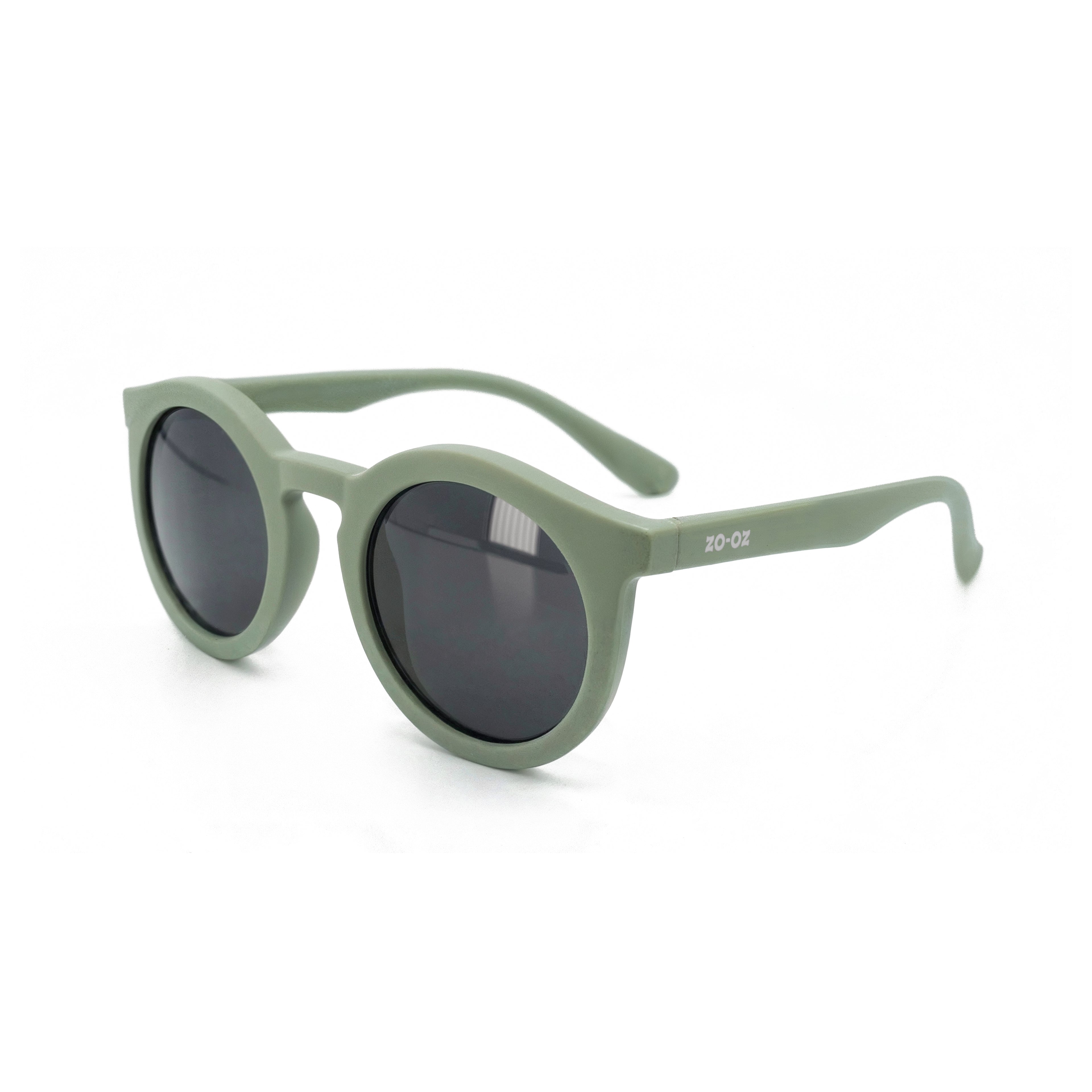Occhiali da sole zo-oz stile pantos modello Snap verde opaco per bambini 6-12 anni. Inquadratura laterale in prospettiva con le aste aperte appoggiate su una superficie.