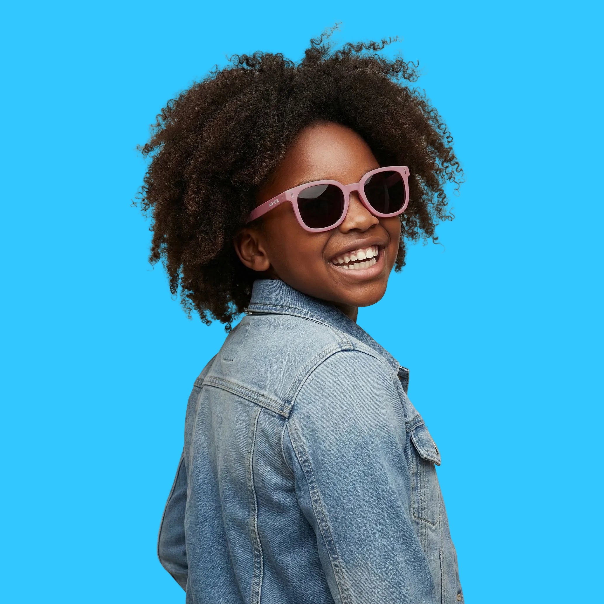 Bambina che indossa gli occhiali da sole neri modello Zip di zo-oz montatura stile Wayfarer. Vista laterale che mostra come calzano sul viso nella fascia 6-12 anni.